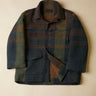 Plaid jacket with a mix of green, brown, and blue colors on a beige background