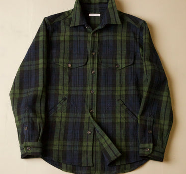 Green and black and navy plaid shirt on a beige background