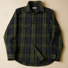 Green and black and navy plaid shirt on a beige background
