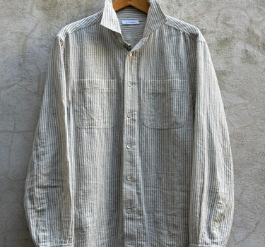 Striped natural shirt on a hanger against a textured wall