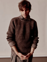 Man wearing a brown knitted sweater against a plain background