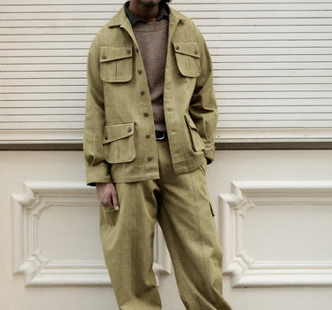 A man wearing a matching khaki olive green utility jacket and trousers set.
