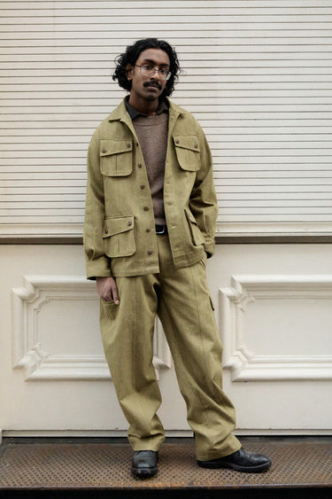 A man wearing a matching khaki olive green utility jacket and trousers set.