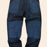 A pair of handwoven cotton pants featuring a hand embroidered running stitch pattern with indigo and iron space dyes, and contrasting fabric double knee and patch pockets.