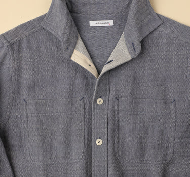 Ligh blue gray shirt with button details on a beige background