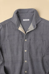 Ligh blue gray shirt with button details on a beige background