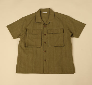 Green shirt with short sleeves and two front pockets on a beige background
