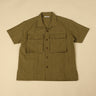 Green shirt with short sleeves and two front pockets on a beige background