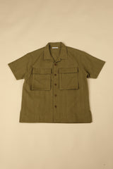 Green shirt with short sleeves and two front pockets on a beige background