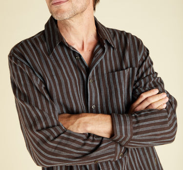 Man wearing a plum and indigo striped shirt against a beige background