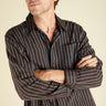 Man wearing a plum and indigo striped shirt against a beige background