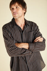 Man wearing a plum and indigo striped shirt against a beige background