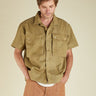 Man wearing a green short-sleeve shirt with button details on a beige background