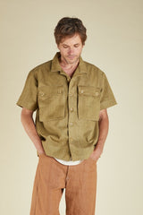 Man wearing a green short-sleeve shirt with button details on a beige background