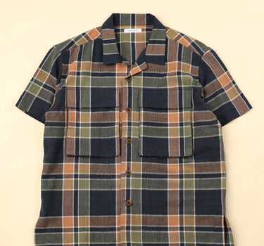 Flat dark blue green and beige plaid shirt on a beige background