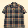Flat dark blue green and beige plaid shirt on a beige background