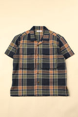 Flat dark blue green and beige plaid shirt on a beige background