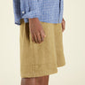Person wearing a blue checkered shirt and beige shorts on a beige background