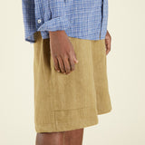 Person wearing a blue checkered shirt and beige shorts on a beige background