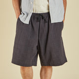 Person wearing dark shorts with a light shirt on a beige background