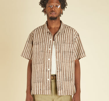 Man wearing a striped shirt and beige pants against a beige background