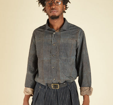 Man wearing a striped shirt and pants with a belt on a beige background