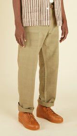Person wearing green pants and brown shoes on a beige background