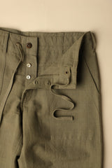 Close-up of olive green pants with buttons on a beige background