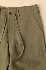Close-up of olive green pants with a beige background