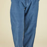 Person wearing blue pants with a drawstring and a light gray shirt on a beige background