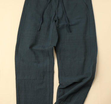 Dark green pants laid flat on a beige background