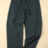 Dark green pants laid flat on a beige background