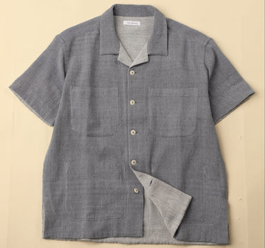 Light blue gray short-sleeve shirt with button details on a beige background