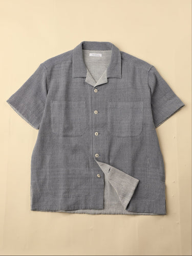 Light blue gray short-sleeve shirt with button details on a beige background