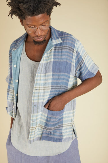 Man wearing a blue plaid shirt over a gray t-shirt on a beige background