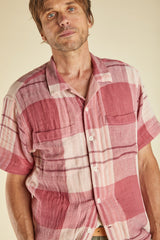 Man wearing a pink and white checkered shirt against a beige background