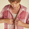Man wearing a pink and white checkered shirt against a plain background