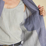 Person wearing a light gray tank top and blue jacket on a beige background
