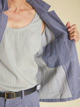 Person wearing a light gray tank top and blue jacket on a beige background