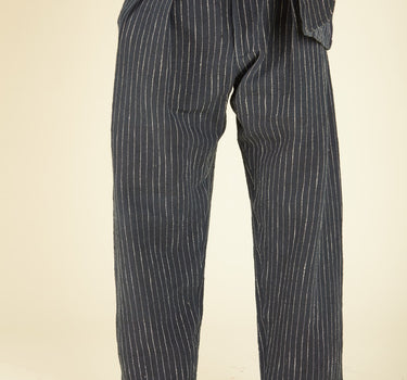 Person wearing a dark pinstripe suit with a beige background