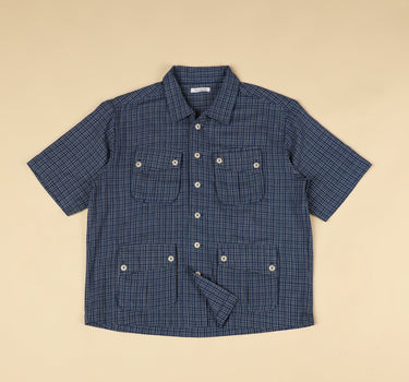 Blue gingham checkered shirt with short sleeves on a beige background