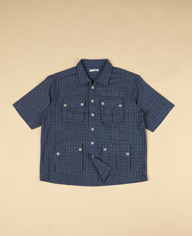 Blue gingham checkered shirt with short sleeves on a beige background