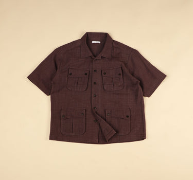 plum short-sleeve shirt with multiple pockets on a beige background