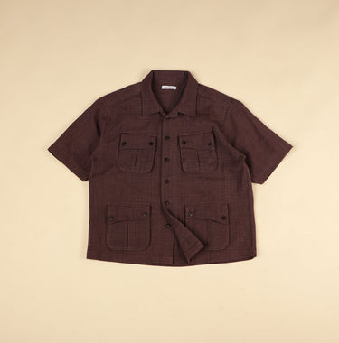 plum short-sleeve shirt with multiple pockets on a beige background