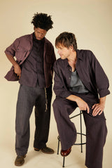 Two people wearing matching dark outfits against a plain background