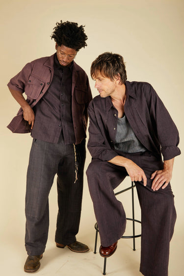 Two people wearing matching dark outfits against a plain background