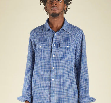 Man wearing a blue checkered shirt against a beige background