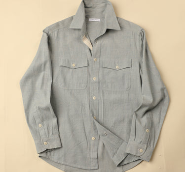 Flat light blue natural chambray shirt on a beige background