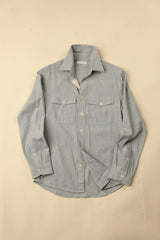 Flat light blue natural chambray shirt on a beige background