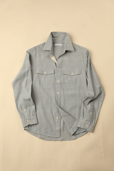 Flat light blue natural chambray shirt on a beige background
